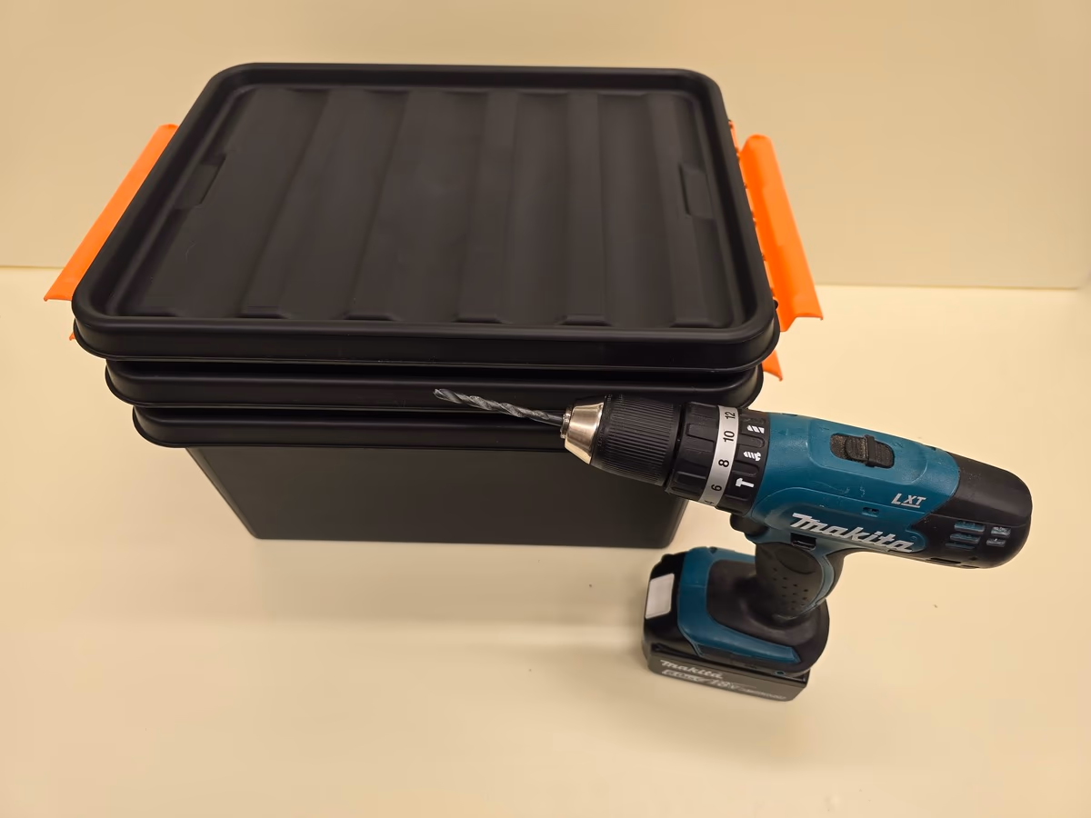 Kolme päällekkäin pinottua SmartStore-laatikkoa ja porakone valmiina matokompostin rakentamiseen