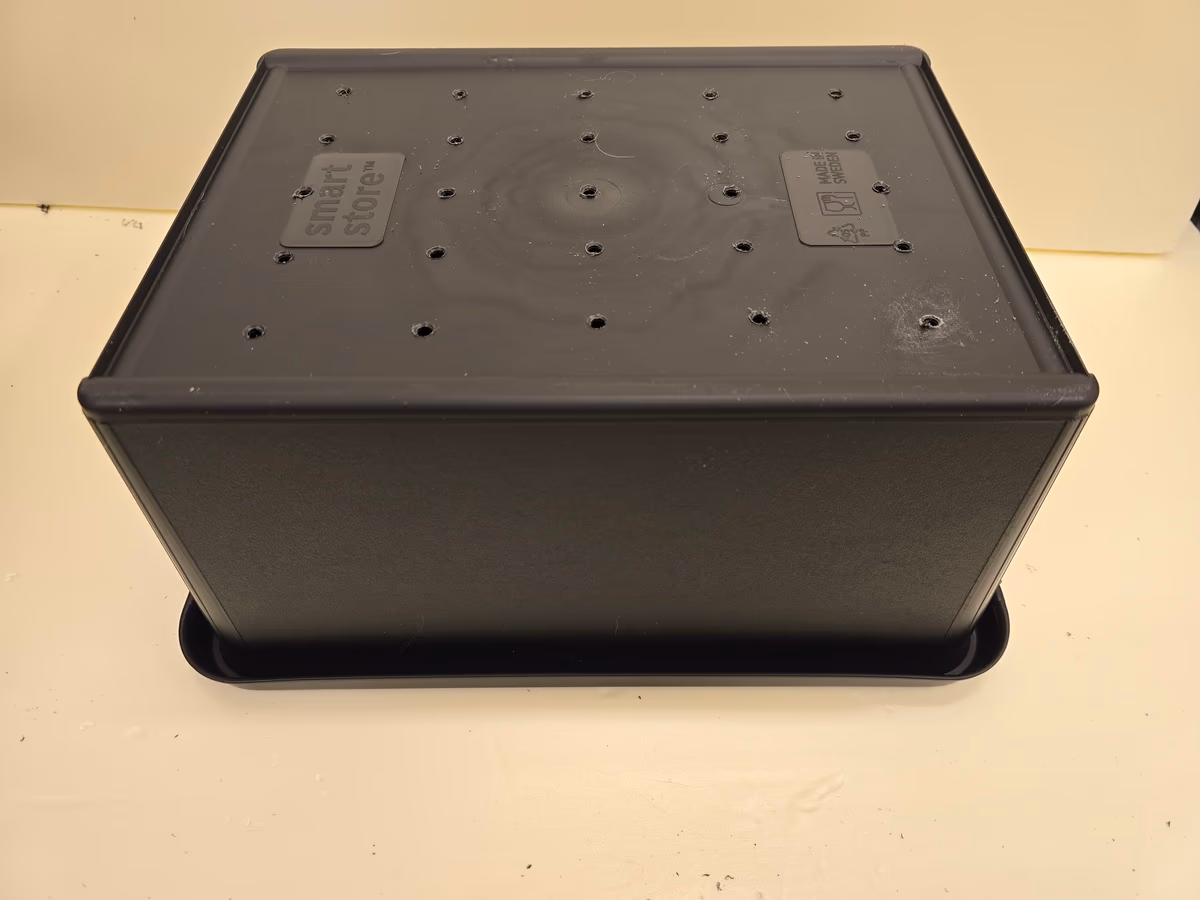 Laatikon pohja, jossa useita tasaisesti porattuja reikiä